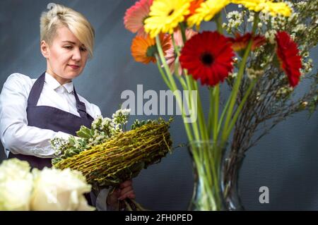 Frau Floristin im Blumenladen sammelt Blumen in einem Strauß Stockfoto