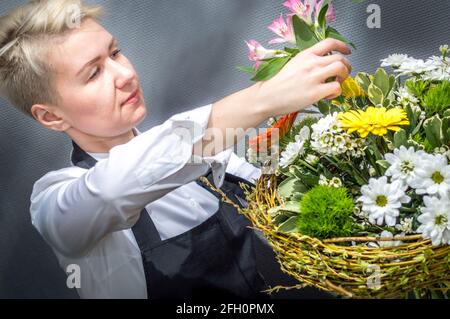 Die junge Frau sammelt Blumen in einem Strauß. Nahaufnahme. Konzept-Blumengeschäft Stockfoto