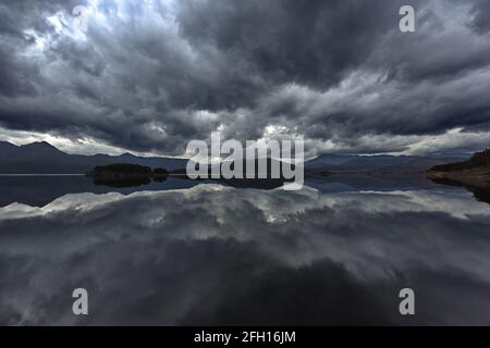 Wunderschöne Sturmwolken und Berge der West Coast Range spiegeln sich in den stillen Gewässern des Lake Burbury in Tasmanien, AU, in blauen, grauen und weißen Farbtönen wider Stockfoto