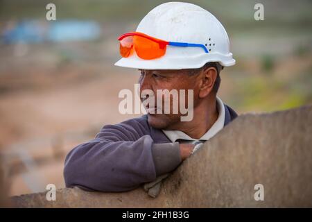 Goldbergbau- und Verarbeitungsanlage der Firma Altynalmas. Porträt eines erwachsenen asiatischen Arbeiters in weißem Hardhut, orangefarbener Schutzbrille. Kasachstan. Stockfoto