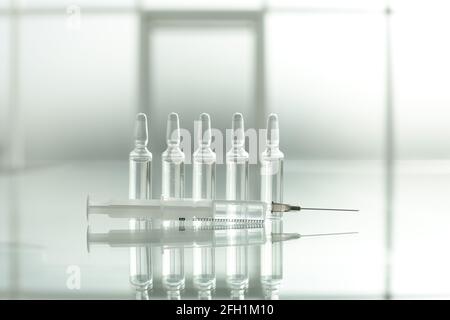Medikamentenfläschchen und Spritze auf Glastisch Stockfoto