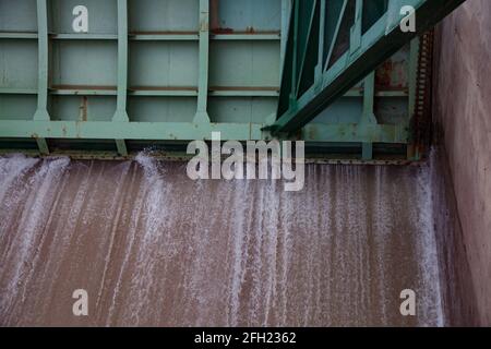 Aklak-Staudamm am Fluss Shardara. Halb offener grüner Stahlwasserverschluss des Staudamms. Starker Strom. Kasachstan, Region Kzylorda. Stockfoto