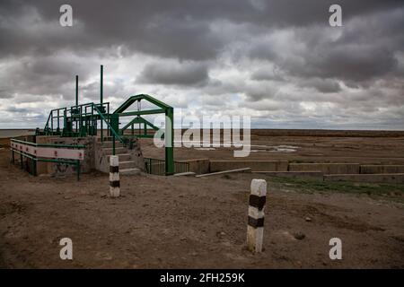 Aklak-Staudamm am Fluss Shardara. Kleiner manueller Wasserverschluss. Dunkelgraue Sturmwolken. Kasachstan, Region Kzylorda. Stockfoto