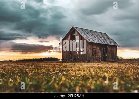 Alte Scheune, die während des Sonnenuntergangs spät auf offenem Ackerland steht Abend im April Stockfoto