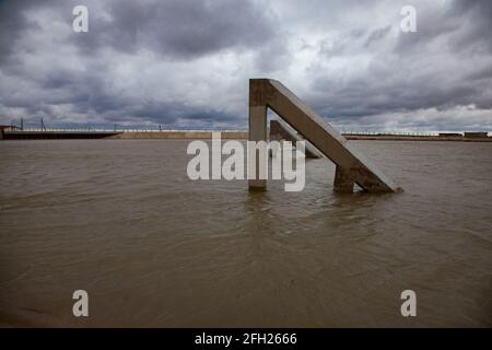 Aklak-Staudamm am Fluss Shardara.Betonbrecher im Kanal Nahaufnahme. Graue, stürmische Wolken. Kasachstan, Region Kzylorda. Stockfoto