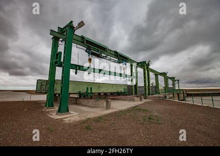 Aklak-Staudamm am Fluss Shardara. Hebevorrichtung von Metallgewichten für Wasserverschluss. Grauer, stürmischer Himmel. Kasachstan, Region Kzylorda. Stockfoto