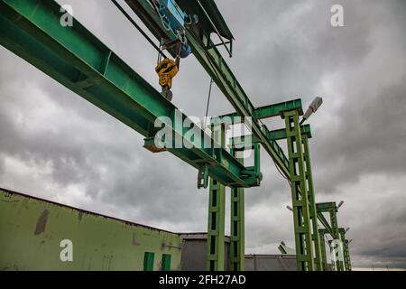 Aklak-Staudamm am Fluss Shardara. Hebevorrichtung von Metallgewichten mit Wasserverschluss. Gelber Kranhaken. Graue Sturmwolken. Kasachstan, Region Kzylorda. Stockfoto