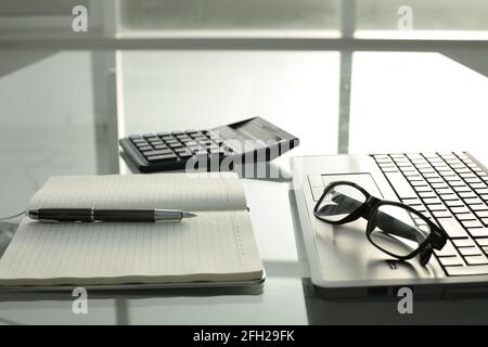 Stift Notizblock Taschenrechner Brille Notizbuch auf Glastisch Stockfoto