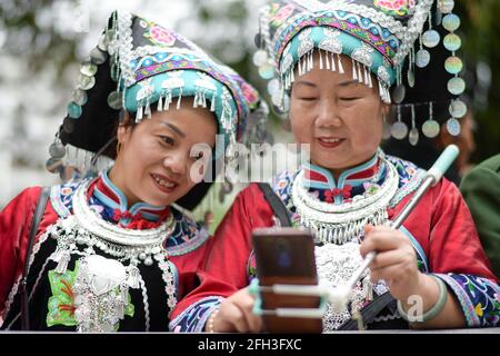 Taijiang, Chinas Provinz Guizhou. April 2021. Zwei Frauen machen ein Selfie, während sie an einer Parade zur Feier des Miao-Schwestern-Festivals im Bezirk Taijiang, Qiandongnan, Miao und der autonomen Präfektur Dong, südwestlich der Provinz Guizhou, teilnehmen, 25. April 2021. Das als nationales immaterielles Kulturerbe anerkannte Miao Sisters Festival wird jährlich um den 15. Tag des dritten Mondmonats nach dem Mondkalender in China gefeiert. Quelle: Yang Ying/Xinhua/Alamy Live News Stockfoto