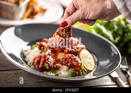 Würzig glasierte Hähnchenschenkel und Flügel mit Reis und Korianderblättern serviert. Stockfoto