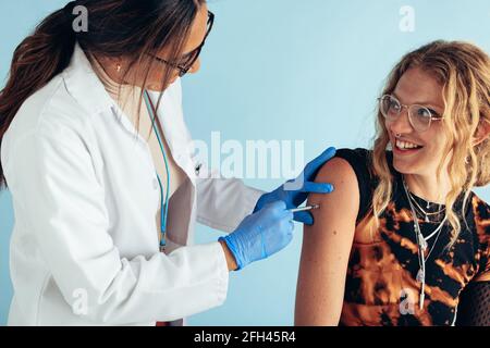 Frau bekommt von einer Ärztin eine Injektion auf den Arm. Frau wird geimpft. Stockfoto