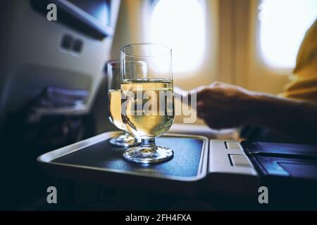 Dring während des Fluges. Zwei Trinkgläser Sekt vor dem Flugzeugfenster. Stockfoto