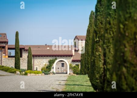 Schöne Aussicht auf ein Landhaus mit Wiesen und Auffahrt mit Zypressen, blauer Himmel im Hintergrund. Frühling auf dem Land mit der Natur rundherum. Stockfoto