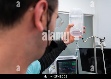 Seitenansicht des männlichen Tierarztes in Stoffmaske Mit einem medizinischen Tropf gegen ein Haustier nach einer Operation in der Klinik Stockfoto