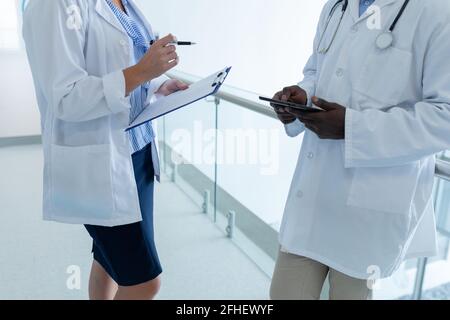 Mittelteil von verschiedenen männlichen und weiblichen Ärzten halten Dokument und Tablet auf dem Krankenhausflur Stockfoto