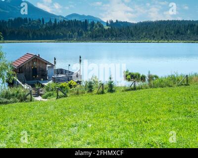 Kleines Fischerhaus mit Steg und Terrasse am bayerischen Attlesee in der Nähe der Stadt Nesselwang. Stockfoto