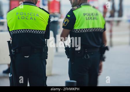 Spanische Polizeieinheit, Rückansicht mit Logo der lokalen Polizei auf Uniform, Aufrechterhaltung der öffentlichen Ordnung in den Straßen von Alicante, Spanien Stockfoto