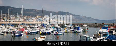 Panoramablick auf den Strand von Lyme Regis durch Yachten und Boote, die am 21. April 2021 im Hafen von Cobb in Lyme Regis, Dorset, Großbritannien, festgemacht wurden Stockfoto