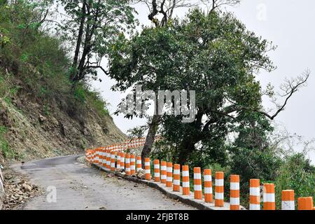Asphaltstraße auf dem Hügel und schöne Bäume mit reflektierenden Säulen Wachen. Stockfoto
