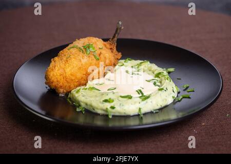 Kartoffelpüree mit Kotelett auf Kiew auf einem schwarzen Teller. Stockfoto