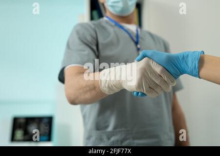 Nahaufnahme von nicht erkennbaren Chirurgen in Handschuhen, die nach erfolgreichem Erfolg die Hände schütteln Betrieb Stockfoto