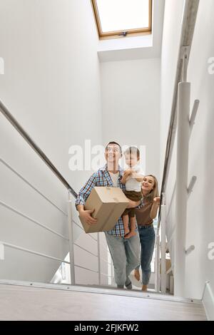 Glückliche Familie mit einem Sohn, der Kisten trug, die die Treppe hinauf ins neue Zuhause gingen. Stockfoto