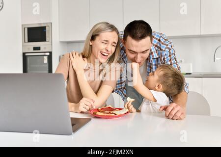 Glückliche junge Familie mit Kind Sohn Spaß beim Essen Toast in der Küche. Stockfoto