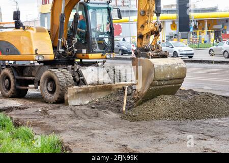 Ein schwerer Straßenbagger plattet bei der Reparatur eines Straßenabschnitts mit einem Eimer einen Schutthaufen. Stockfoto