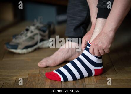 Der Mann setzt bunt gestreifte Socken und Schuhe gezeigt Im Hintergrund Stockfoto