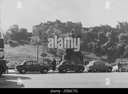 1956, historisch, Schottland, Edinburgh, ein Blick auf die Princes Street, mit Autos aus der Zeit, die an der Royal Grey's Gedenkstatue geparkt sind, mit dem berühmten Schloss im Hintergrund. Die Statue wurde 1906 enthüllt und erinnert an die Royal Scot Grays, die die Stadt verließen, um im Boer-Krieg, 1899 und in anderen früheren Militärcampiagns in Südafrika zu kämpfen. Das Edinburgh Castle ist das Regimental-Hauptquartier der Royal Scots Dragoon Guards. Stockfoto