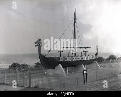 1958, das Wikingerschiff oder Langboot "Hugin", das an der Küste auf der Pegwell Bay Klippe, Ramsgate, Kent, England, Großbritannien, ausgestellt wird. Ein rekonstruiertes Langschiff, die Hugin, ein Geschenk des dänischen Schenkers zum Gedenken an den 1500. Jahrestag von Hengist und Horsa, Anführer der angelsächsischen Invasion in der nahegelegenen Ebbsfleet, kam 1949 in Viking Bay, Broadstairs an. Es ist eine Nachbildung des Gokstad-Schiffes, ca. 890. Stockfoto