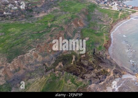 Steile Küste und Brandung. Das Meerwasser war nach Sturm und Algen schlammig mit Sand. Luftaufnahme. Stockfoto