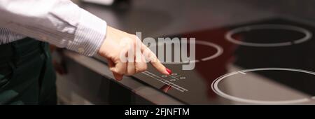 Weibliche Finger drückt Taste auf Touch-Elektroherd Stockfoto