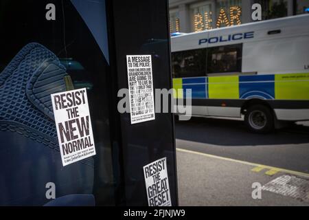 24. April 2021, London, England, Vereinigtes Königreich: Bushaltestelle mit Aufklebern und Polizeiwagen, der während eines Anti-Lockdown-Protests in London vorbeifährt. Stockfoto