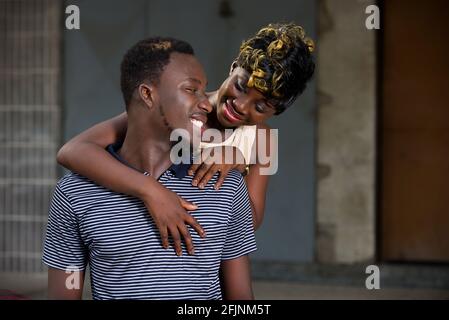 Junges afrikanisches Paar, das vor dem Haus lächelnd und umarmt. Stockfoto