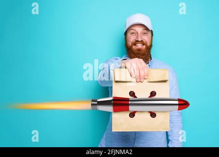 Deliveryman mit wunderten Ausdruck bereit, schnelle Tasche mit Lebensmitteln wie eine Rakete liefern. Cyan Hintergrund. Stockfoto