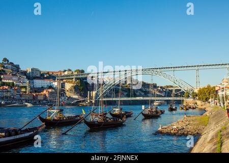 Lastkähne auf dem Fluss Douro in Porto, mit dem Dom Luis Brücke im Hintergrund, Portugal. Stockfoto