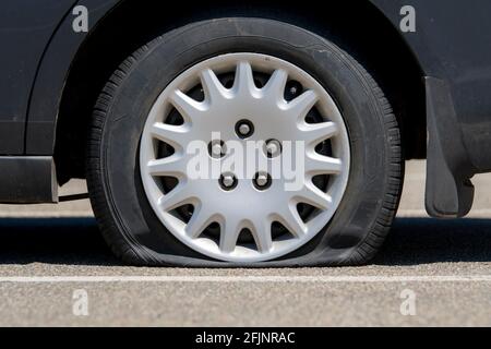 Reifenpanne auf einem schwarzen Auto. Nahaufnahme mit niedrigem Winkel. Stockfoto