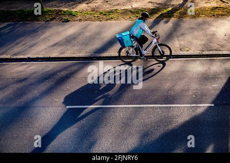 Ein Radfahrer wirft am späten Nachmittag einen langen Schatten Sonnenschein Stockfoto