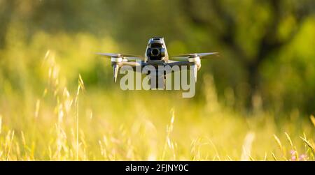 Atemberaubende Aussicht auf eine FPV-Drohne, die während eines wunderschönen Sonnenuntergangs über einem Grasfeld fliegt. Konzept der Freizeitbeschäftigungen, Hobby. Stockfoto
