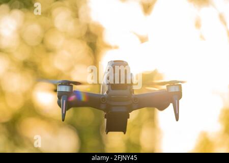 Atemberaubende Aussicht auf eine FPV-Drohne, die während eines wunderschönen Sonnenuntergangs über einem Grasfeld fliegt. Konzept der Freizeitbeschäftigungen, Hobby. Stockfoto