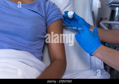 Mittelteil der kaukasischen Ärztin im Krankenhaus, die afroamerikaner impft Weibliche Patientin Stockfoto