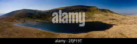 Panorama-Luftaufnahme eines wunderschönen gletscherförmigen Sees am Fuße eines Berges (Llan y Fan Fawr). Brecon Beacons, Wales Stockfoto