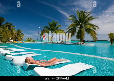 Frau Sonnenbaden am Pool, Kandooma Island, Süd Male Atoll, Schwimmbad, Pool, Sonnenliege, Malediven Stockfoto