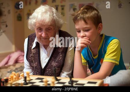 Eine alte Frau spielt mit ihrem kleinen Enkel Schach. Stockfoto