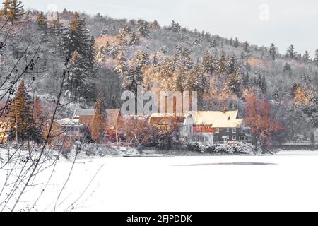 Malerische Stadt am Hang mit Häusern und einer roten Scheune umgeben Von schneebedeckten Bäumen Stockfoto