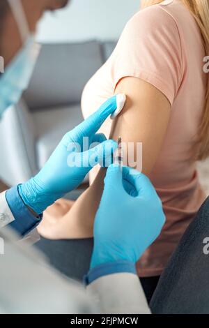Nahaufnahme der Hand des Patienten und der Hand des Arztes, die eine Grippeimpfung einführt Injektion am Arm Stockfoto