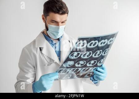 Porträt von Arzt weißen Mantel, medizinische Handschuhe und in Maske Blick auf Lunge Röntgen Stockfoto