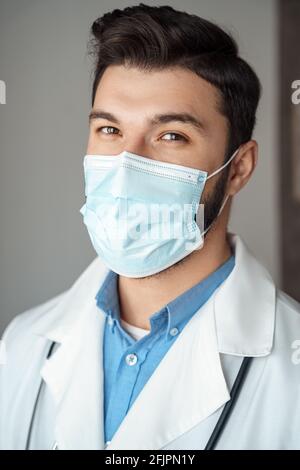 Porträt eines kaukasischen jungen Arztes mit einem freundlich lächelnden Gesicht Schutzmaske Stockfoto