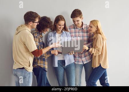 Happy teen Mädchen zeigt Laptop zu lächelnden Teenager Freunde Studio Hochformat Stockfoto